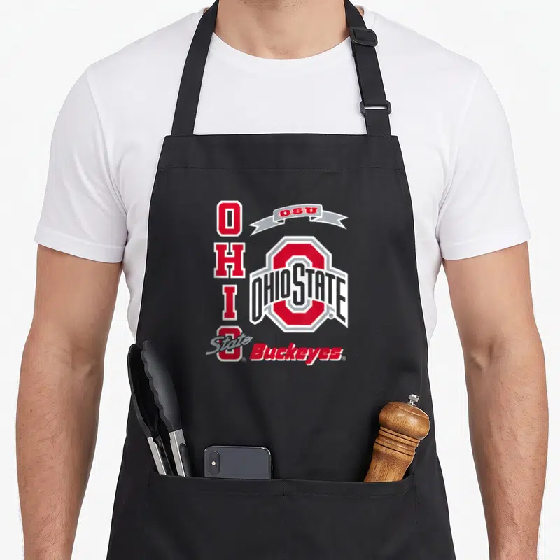 Cool buckeye apron - Red white and grey Ohio State logo with vertical OHIO text and OSU ribbon banner — shown on a black cotton canvas apron against a white background