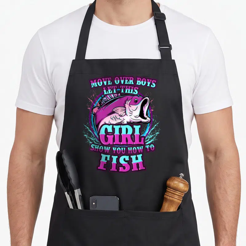 Show fish apron - Purple and pink text surrounding a cartoon fish in a blue circle — shown on a black cotton canvas apron against a white background
