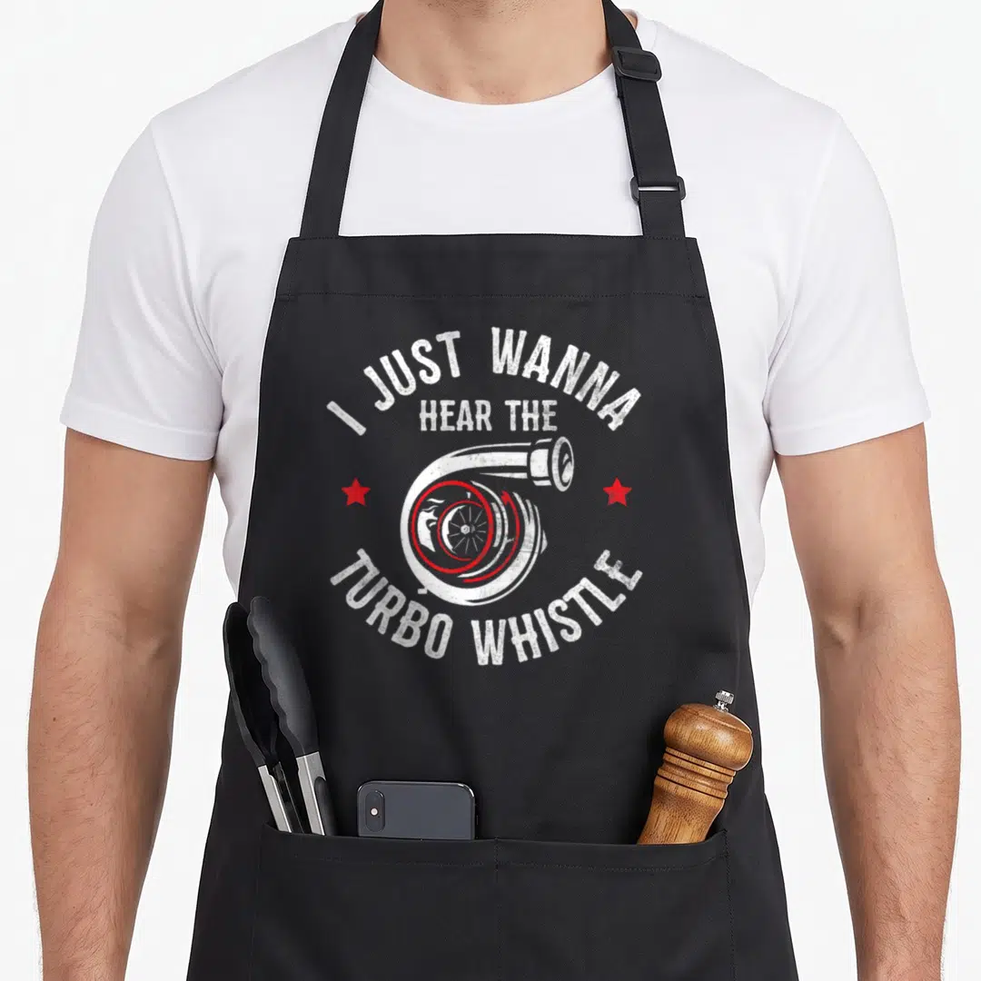 Hear car apron - White turbocharger with red stars and text I JUST WANNA HEAR THE TURBO WHISTLE — shown on a black cotton canvas apron against a white background