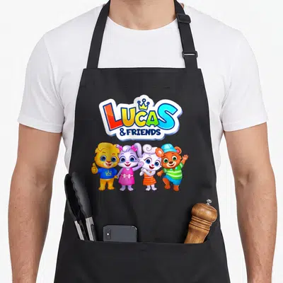 Appstudio friends apron - Four cartoon animals standing below LUCAS & FRIENDS text with a crown icon — shown on a black cotton canvas apron against a white background