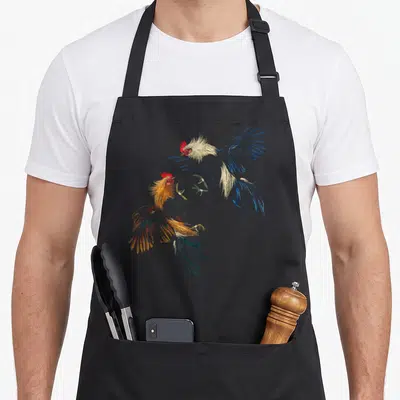 Peleas rooster apron - Two realistic roosters fighting in blue orange and red colors — shown on a black cotton canvas apron against a white background