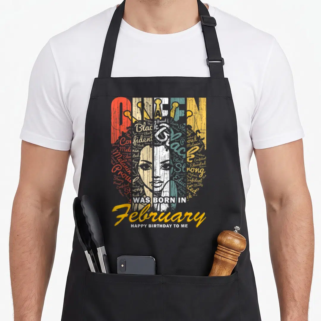 February queen apron - Typographic woman face made of words Confident Proud Strong Black Educated Melanin WAS BORN — shown on a black cotton canvas apron against a white background