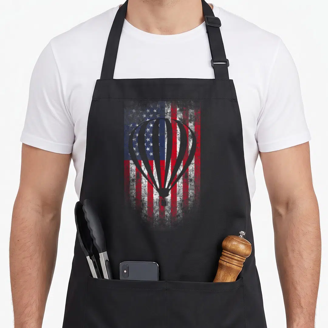 Air flag balloon apron - Grey hot air balloon silhouette over distressed red white and blue American flag pattern — shown on a black cotton canvas apron against a white background
