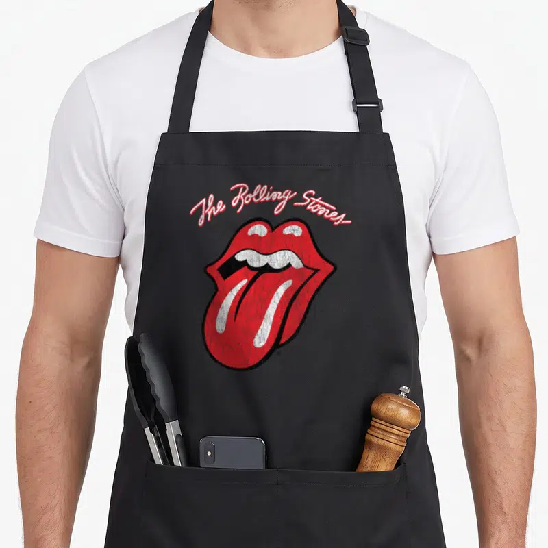 Funny script rolling stones apron - Arched script text above red lips and tongue with distressed texture — shown on a black cotton canvas apron against a white background