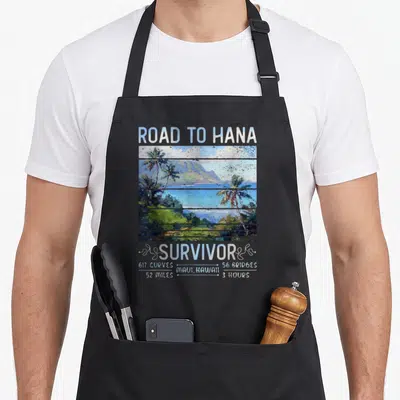 Rjc road apron - Road to Hana Survivor text above blue green landscape with 617 curves and 52 miles stats — shown on a black cotton canvas apron against a white background