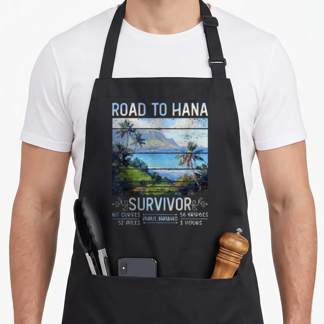 Rjc road apron - Road to Hana Survivor text above blue green landscape with 617 curves and 52 miles stats — shown on a black cotton canvas apron against a white background