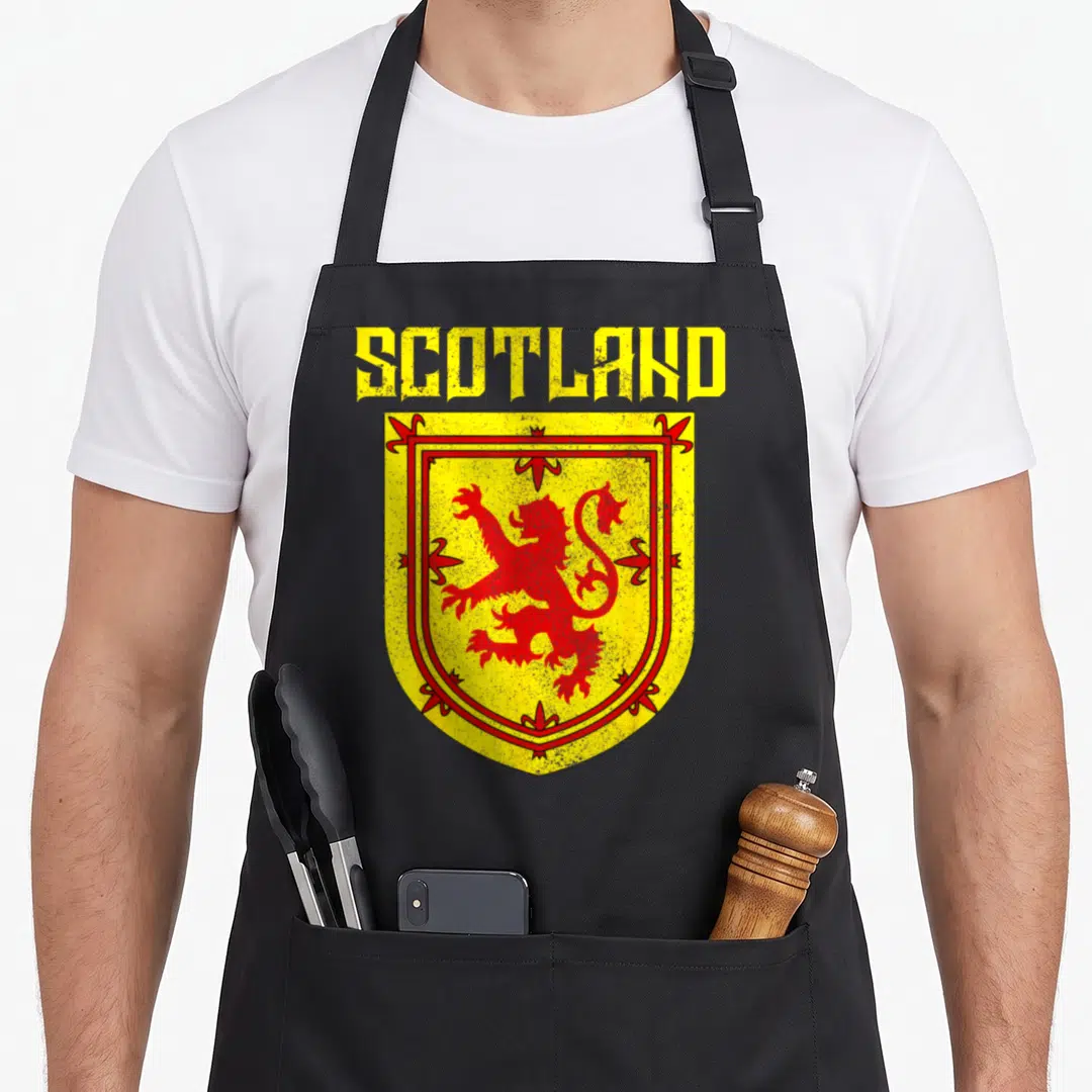 Funny scottish pride apron - Distressed yellow shield with red lion and SCOTLAND text — shown on a black cotton canvas apron against a white background
