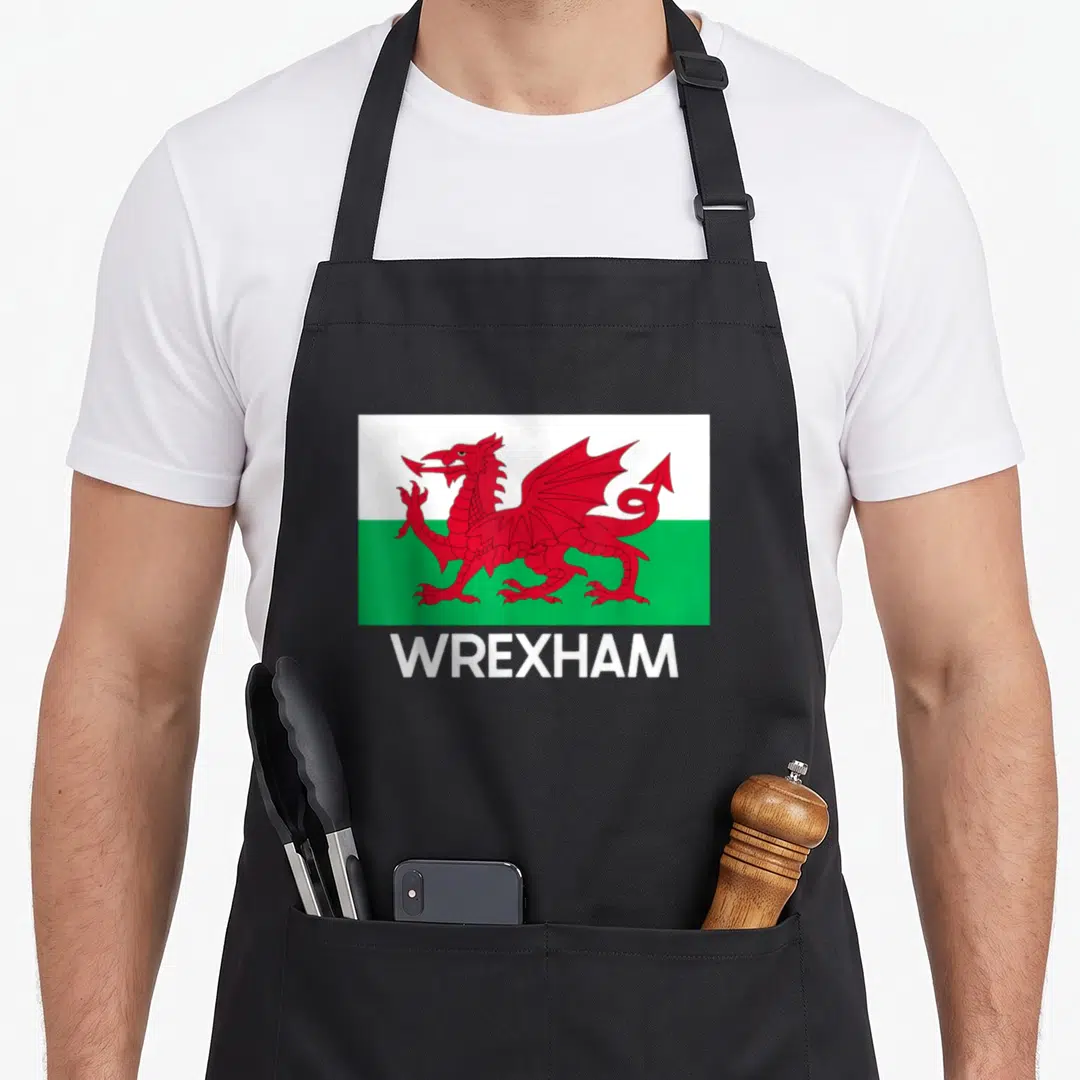 Flag welsh apron - Red dragon on white and green rectangle above white WREXHAM text — shown on a black cotton canvas apron against a white background