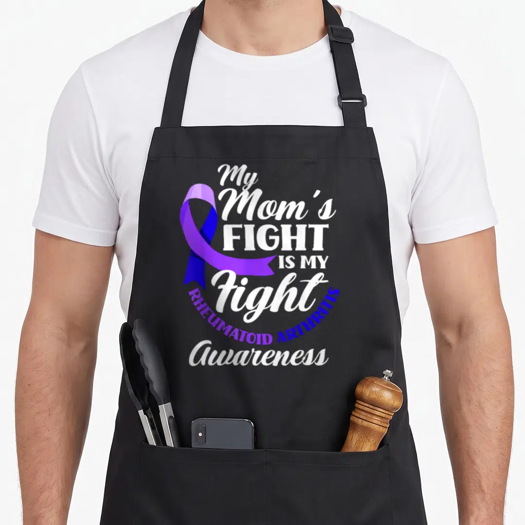 Fight arthritis awareness apron - Purple ribbon and white text reading My Mom's Fight Is My Fight Rheumatoid Arthritis — shown on a black cotton canvas apron against a white background