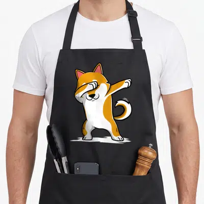Shiba world music apron - Cartoon shiba inu performing the dab dance pose in orange, white, and black — shown on a black cotton canvas apron against a white background