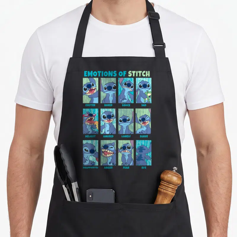 Emotion stitch apron - Stitch character grid with labels EXCITED BORED SHOCK SAD DELIGHT AMUSED LONELY SUAVE — shown on a black cotton canvas apron against a white background