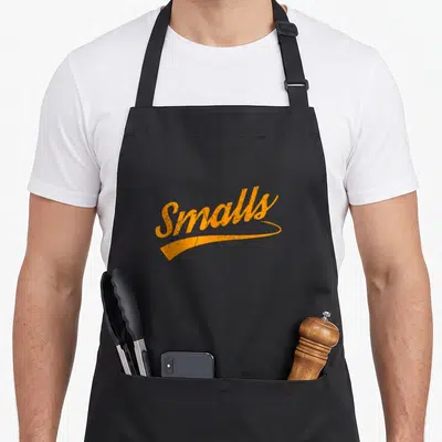 Funny food distressed apron - Orange script text Smalls with distressed texture and underline swoosh — shown on a black cotton canvas apron against a white background