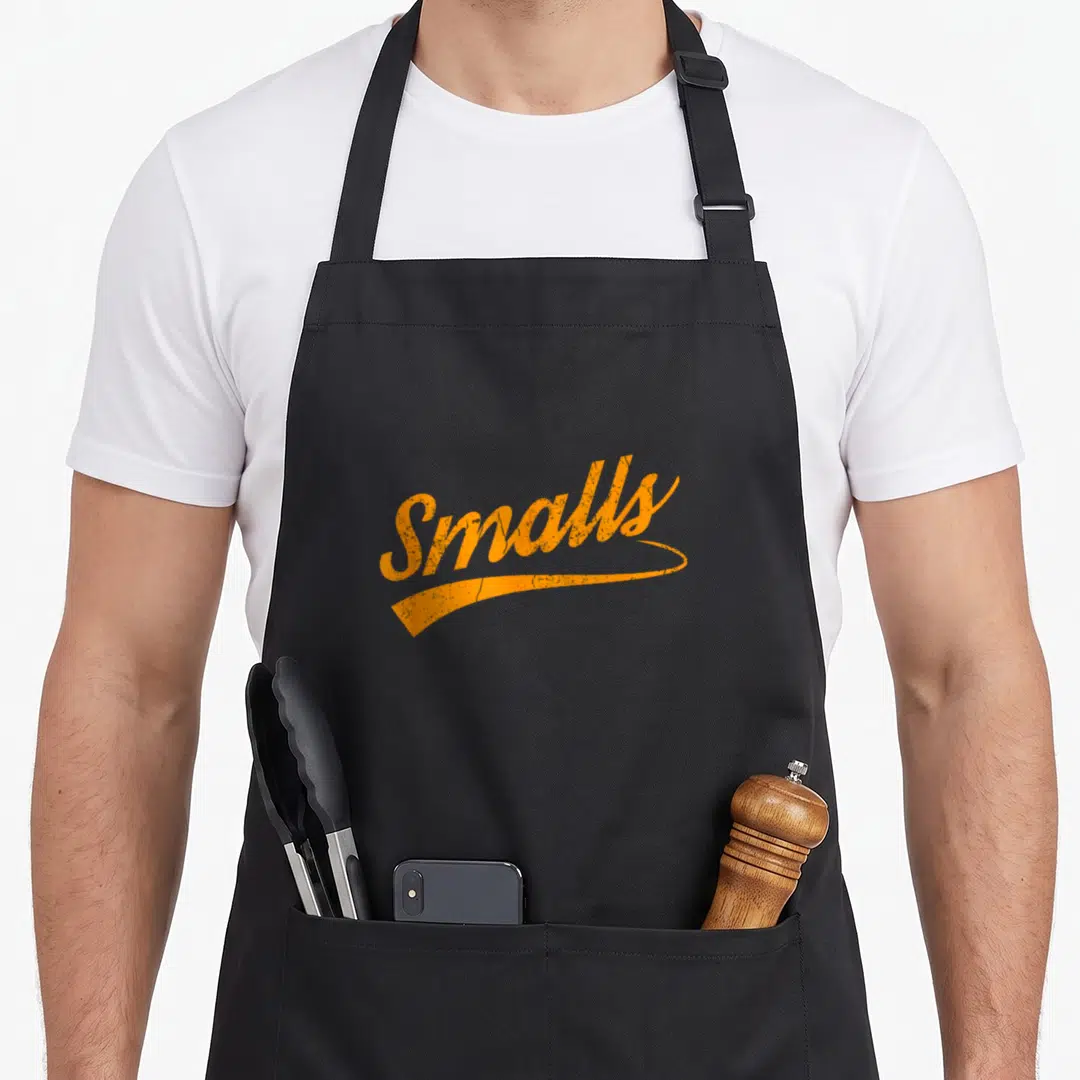 Funny food distressed apron - Orange script text Smalls with distressed texture and underline swoosh — shown on a black cotton canvas apron against a white background