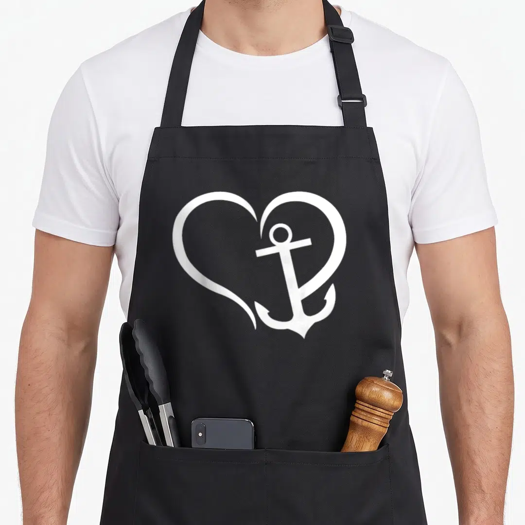 Anchor nautical apron - White anchor inside a heart outline on a black bib apron — shown on a black cotton canvas apron against a white background