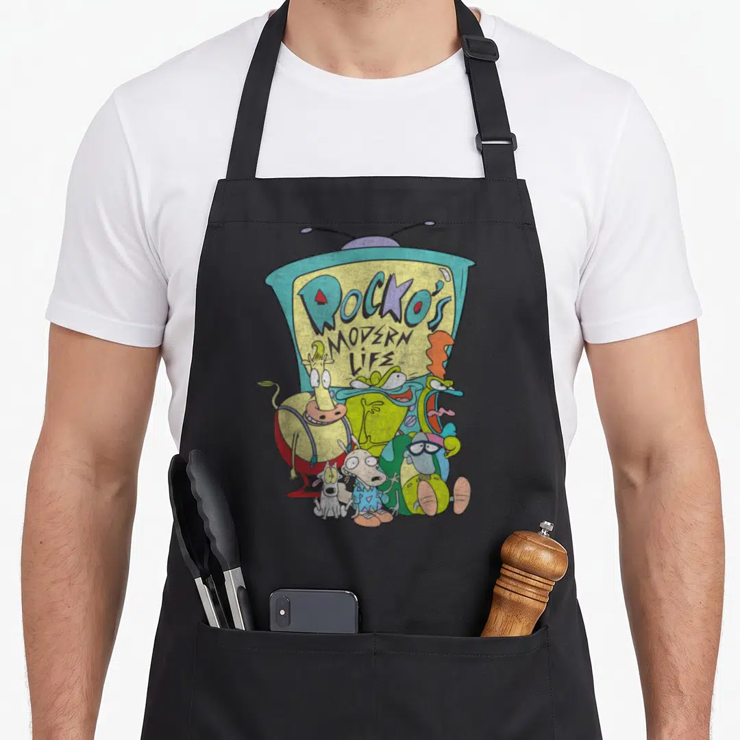 Rocko modern apron - Cartoon characters clustered before a TV set displaying the title text in blue and yellow — shown on a black cotton canvas apron against a white background