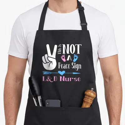 Birth assistant nurse apron - White hand peace sign with pink and blue footprints and L&D Nurse text on black fabric — shown on a black cotton canvas apron against a white background