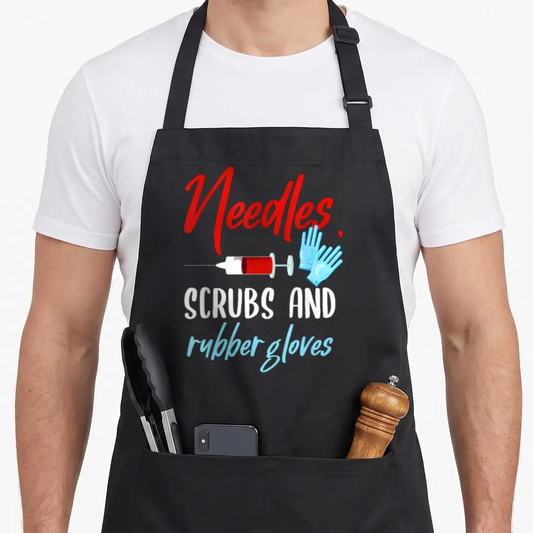 Phlebotomist gloves and apron - Needles, scrub and rubber gloves text with cartoon syringe and blue gloves — shown on a black cotton canvas apron against a white background
