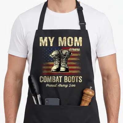 Combat mom and son aprons - Distressed flag background with combat boots and My Mom Wears Combat Boots text — shown on a black cotton canvas apron against a white background