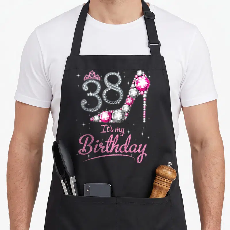 Bday queen apron - Number 38 shaped as a diamond high heel with a crown and pink glitter text — shown on a black cotton canvas apron against a white background