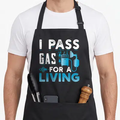 Pass anesthesiologist problems apron - Stacked I PASS GAS FOR A LIVING text with blue anesthesia machine and syringe — shown on a black cotton canvas apron against a white background