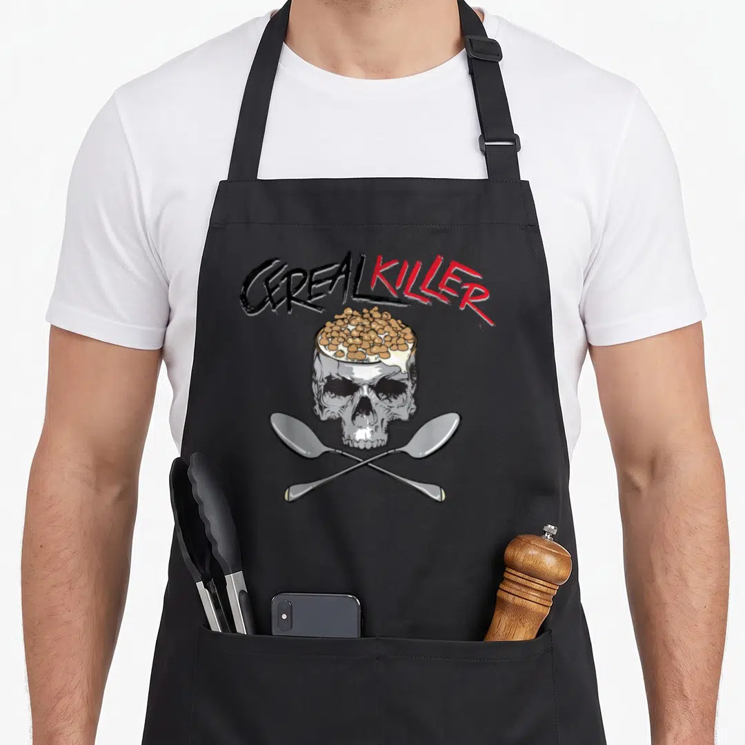 Cereal i love oat apron - Skull filled with cereal and milk above two crossed spoons under CEREAL KILLER text — shown on a black cotton canvas apron against a white background