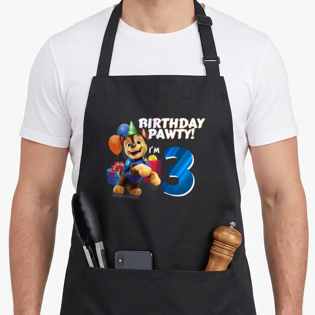 Cute chase birthday apron - Chase wearing party hat next to blue number 3 and gift boxes — shown on a black cotton canvas apron against a white background