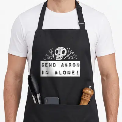 Hunting ghost apron - White skull and plants above banner reading Send Aaron In Alone distressed text — shown on a black cotton canvas apron against a white background