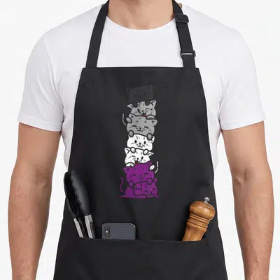 Stack cat apron - Seven cartoon cats stacked vertically in black grey white and purple representing asexual pride — shown on a black cotton canvas apron against a white background