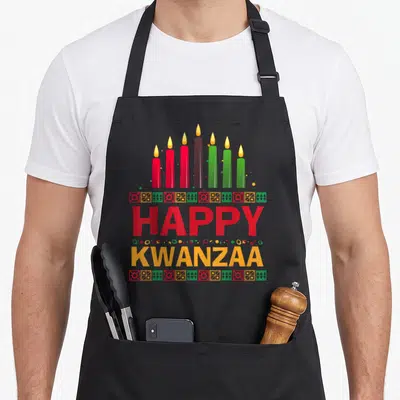 Seven candle african american aprons - Seven red green and black kinara candles above Happy Kwanzaa text with geometric — shown on a black cotton canvas apron against a white background
