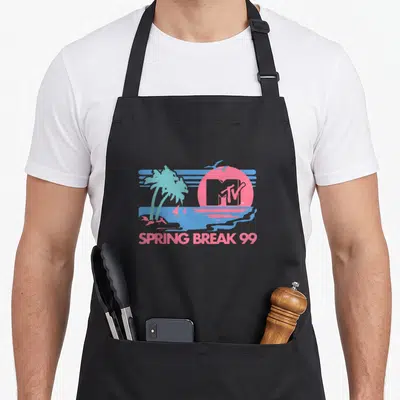 Pastel spring aprons - Pink sun with MTV logo, blue palm trees, ocean scene, and SPRING BREAK 99 text — shown on a black cotton canvas apron against a white background
