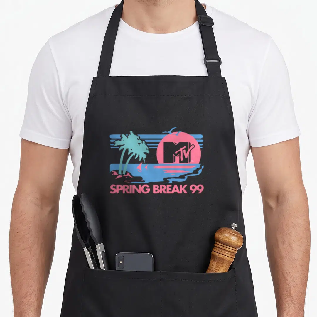 Pastel spring aprons - Pink sun with MTV logo, blue palm trees, ocean scene, and SPRING BREAK 99 text — shown on a black cotton canvas apron against a white background