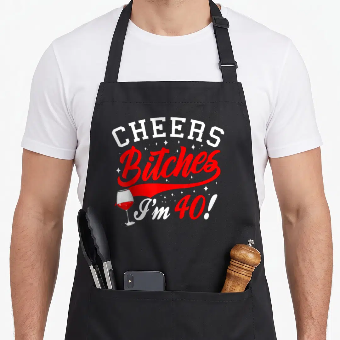 Forty cheer 40th birthday apron - Red and white stacked text CHEERS Bitches I'm 40 with wine glass and stars — shown on a black cotton canvas apron against a white background