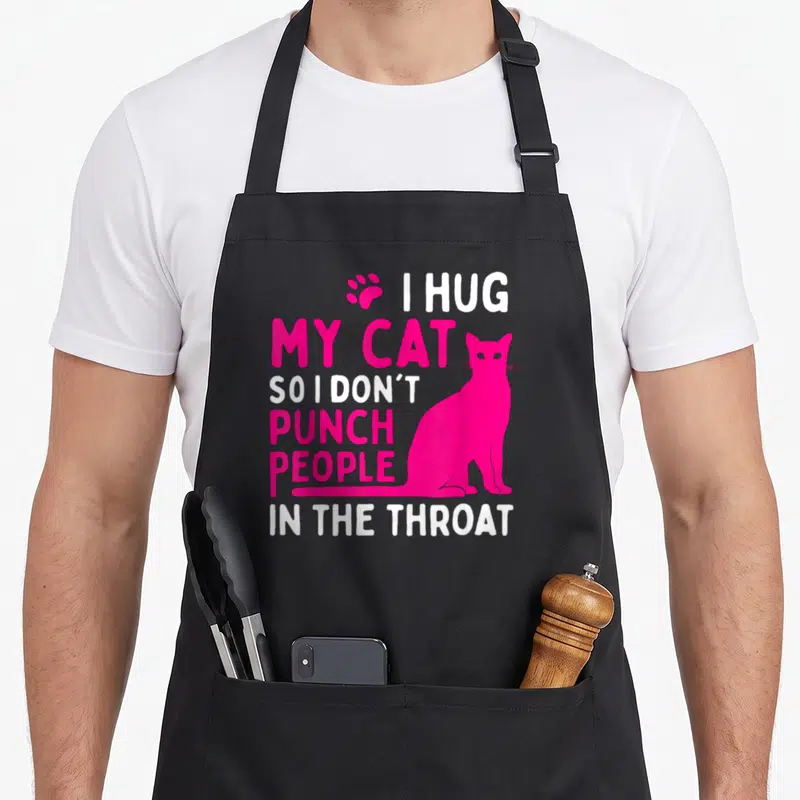 Hug cat apron - Pink and white text I HUG MY CAT SO I DON'T PUNCH PEOPLE IN THE THROAT next to a cat silhouette and paw — shown on a black cotton canvas apron against a white background