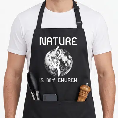 Nature church aprons - White NATURE IS MY CHURCH text framing a grey moon with a central stylized human silhouette — shown on a black cotton canvas apron against a white background