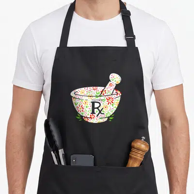 Mortar pharmacist apron - White mortar and pestle with red green floral pattern and grey Rx symbol — shown on a black cotton canvas apron against a white background