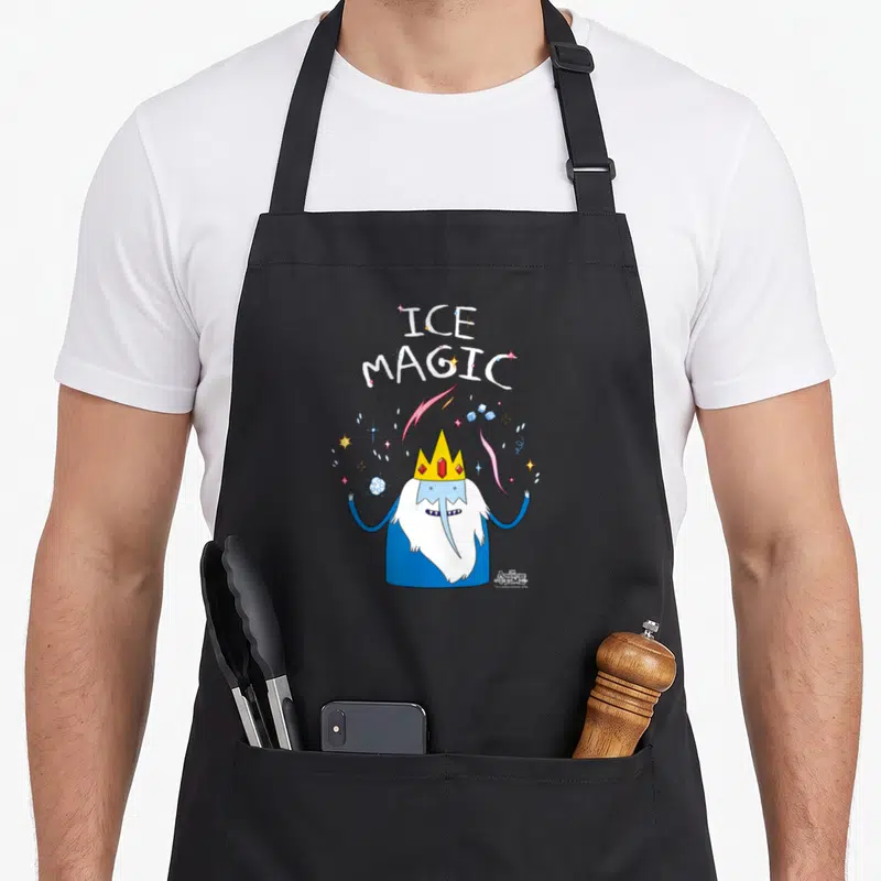 Adventure magic apron - Cartoon wizard with yellow crown and red gems under stacked ICE MAGIC text surrounded — shown on a black cotton canvas apron against a white background