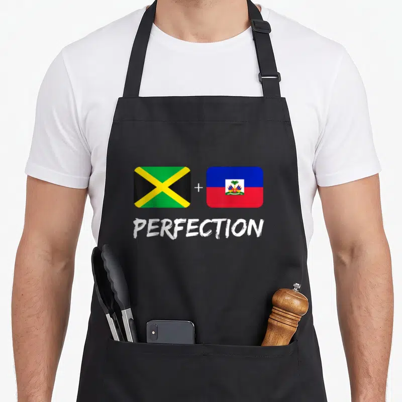 Haitian mix heritage aprons - Jamaican and Haitian flags with plus sign and white text reading PERFECTION — shown on a black cotton canvas apron against a white background