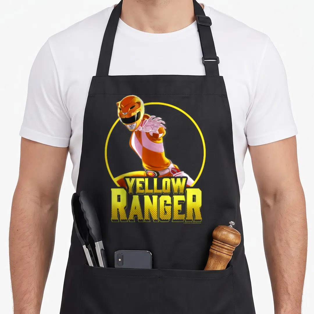 Portrait rangers apron - Yellow Ranger character in yellow circle with stacked YELLOW RANGER text — shown on a black cotton canvas apron against a white background