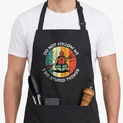 Kayak summer aprons - Retro kayaker in striped circle with DO NOT FOLLOW ME I DO STUPID THINGS text — shown on a black cotton canvas apron against a white background