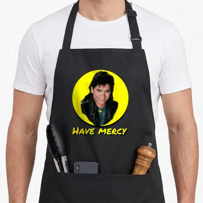 Uncle mercy apron - Photo of a man in a yellow circle above the text HAVE MERCY — shown on a black cotton canvas apron against a white background