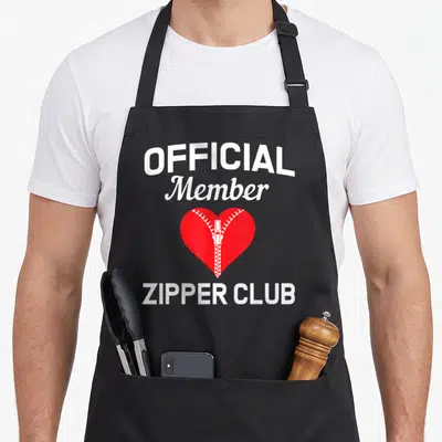 Well open apron - Red heart with white zipper running vertically, arched OFFICIAL Member text and straight ZIPPER CLUB — shown on a black cotton canvas apron against a white background