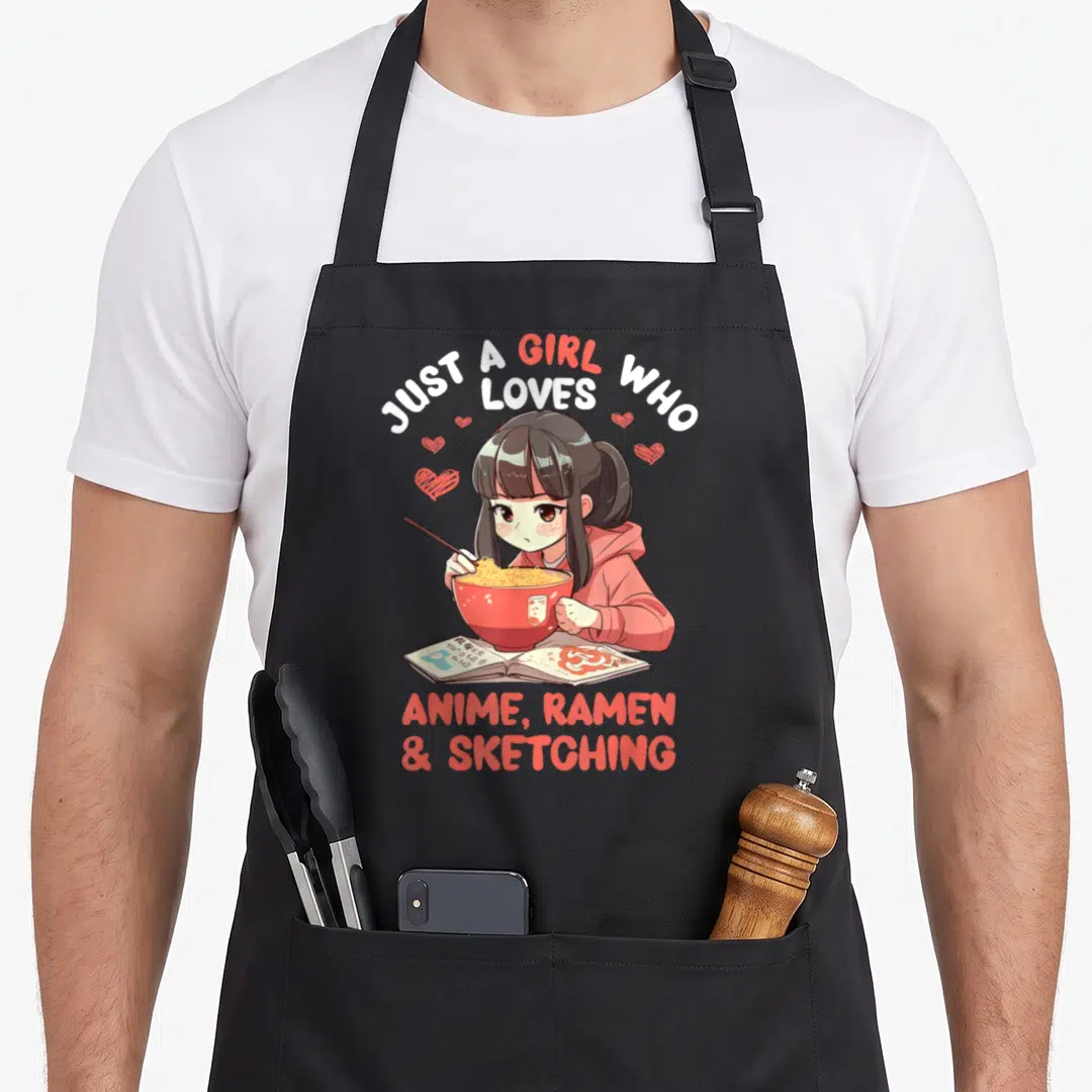 Ramen sketching japan apron - Anime girl eating ramen from red bowl with open sketchbook and hearts — shown on a black cotton canvas apron against a white background