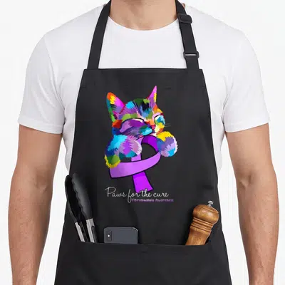 Awareness cat apron - Multicolored cartoon cat hugging purple ribbon with Paws for the cure text — shown on a black cotton canvas apron against a white background