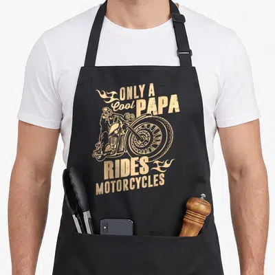 Papa motorcycle apron - Tan distressed motorcycle graphic with flames and text Only a Cool Papa Rides Motorcycles — shown on a black cotton canvas apron against a white background