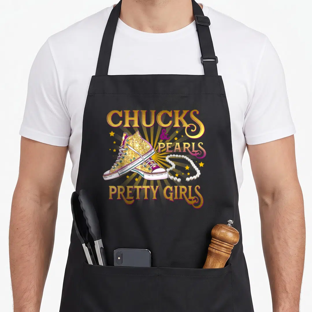 Chuck pretty apron - Gold glitter sneakers and pearl necklace with yellow sunburst and stacked text — shown on a black cotton canvas apron against a white background