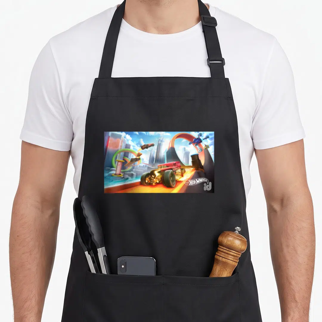 Loop wheel apron - Red car on orange track with cars jumping through loops in futuristic city, HOT WHEELS id logo — shown on a black cotton canvas apron against a white background