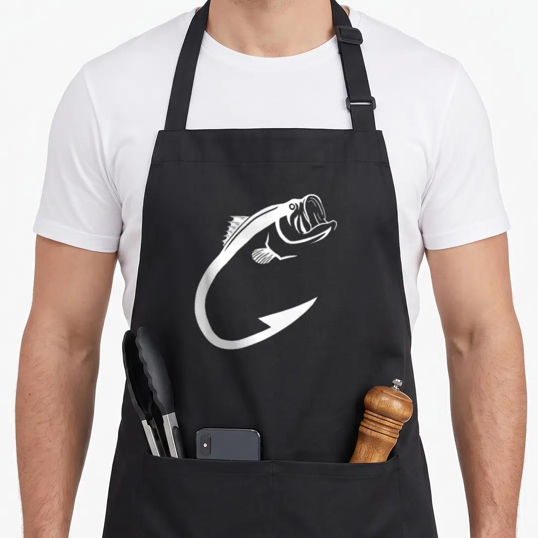 Hook fish apron - White line art of a fish forming the top curve of a large hook — shown on a black cotton canvas apron against a white background