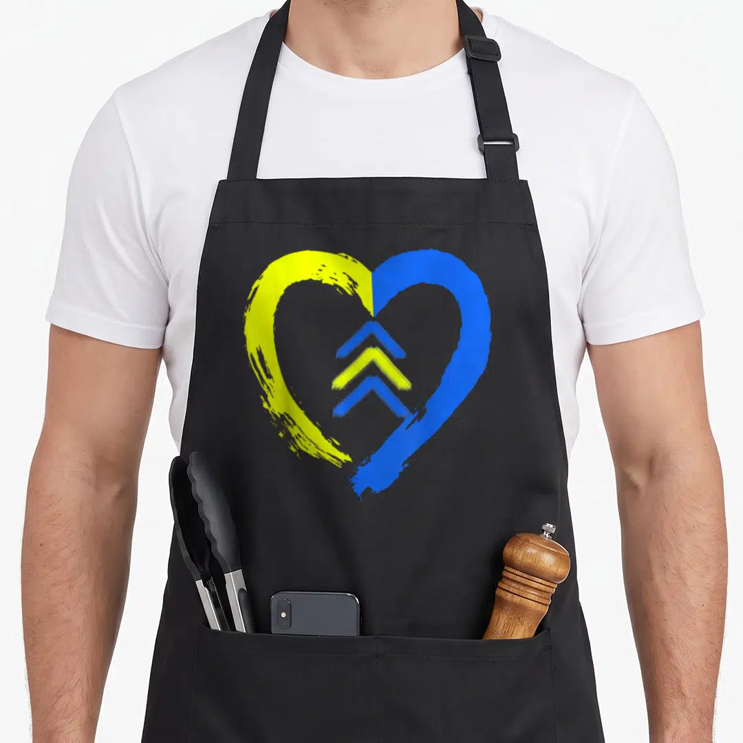 Arrow folk lover apron - Yellow and blue split heart with three stacked chevrons in the center — shown on a black cotton canvas apron against a white background