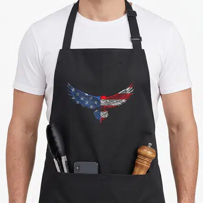 Mullet american flag apron - Cartoon eagle with outstretched wings in blue white and red flag pattern — shown on a black cotton canvas apron against a white background