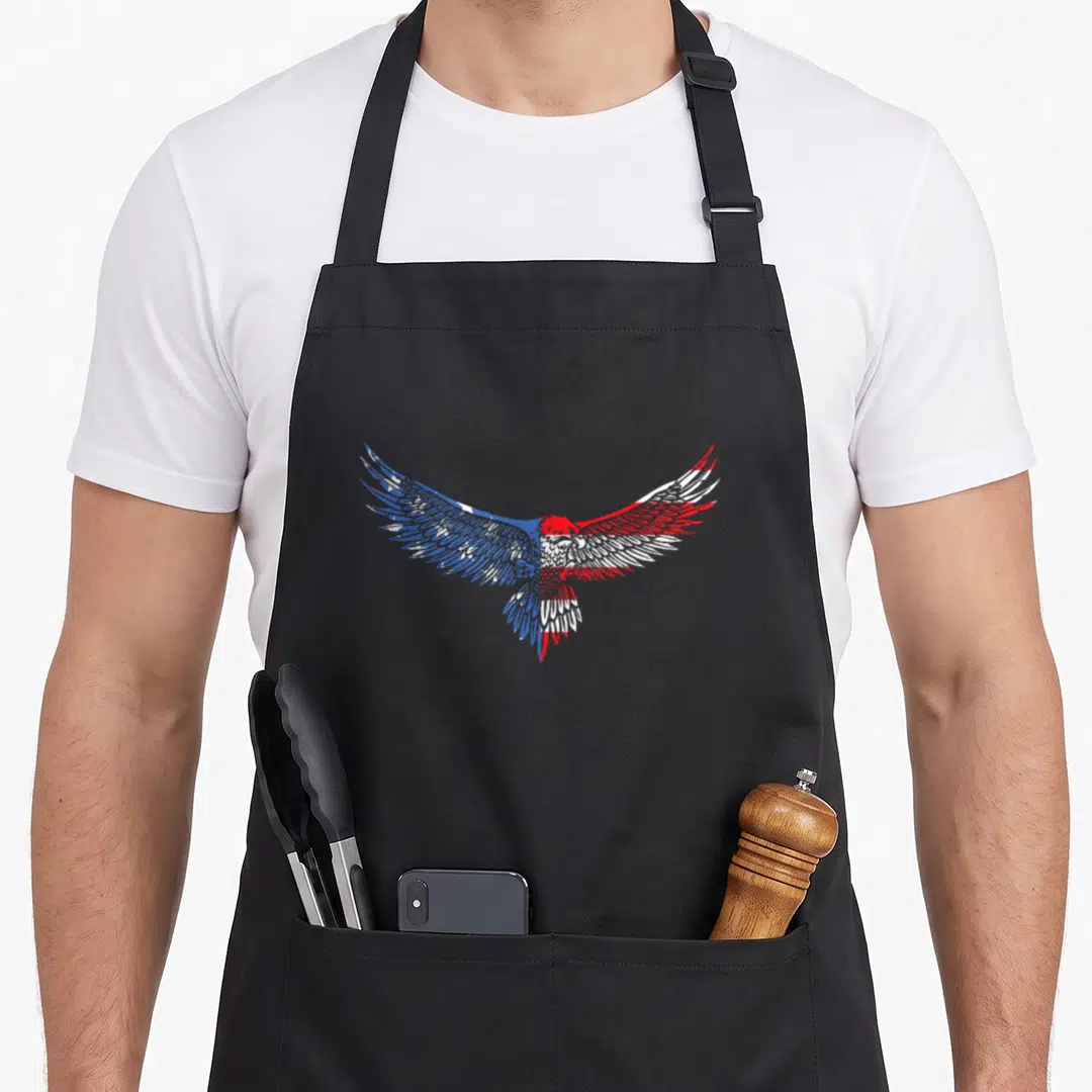 Mullet american flag apron - Cartoon eagle with outstretched wings in blue white and red flag pattern — shown on a black cotton canvas apron against a white background